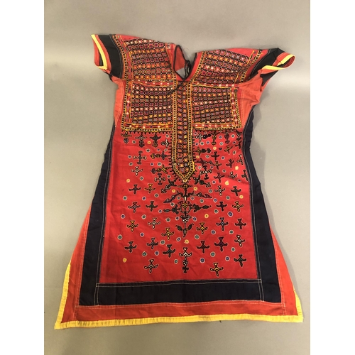 304 - Indian textiles: a cotton over garment for a child, the front extensively and finely embroidered in ... 