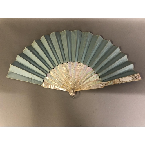 75 - A Brussels bobbin applique lace fan, laid on pale blue silk, the mother of pearl monture of burgau w... 