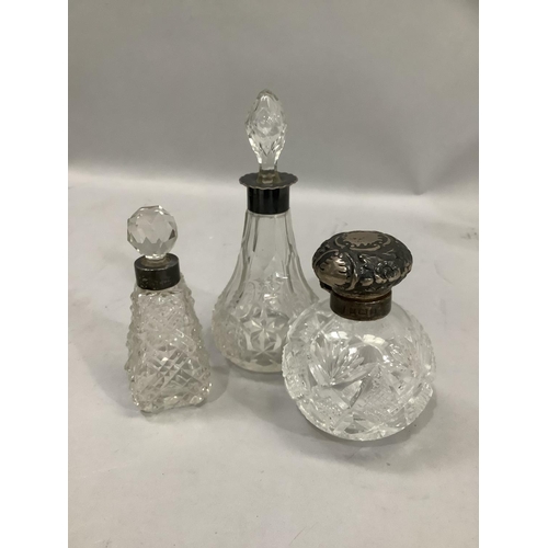 372 - Three cut glass scent bottles with silver collars, and a silver top, hallmarked for Birmingham 1902,... 