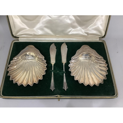 348 - A boxed pair of George V silver butter dishes by Goldsmiths & Silversmiths, each of scallop form on ... 