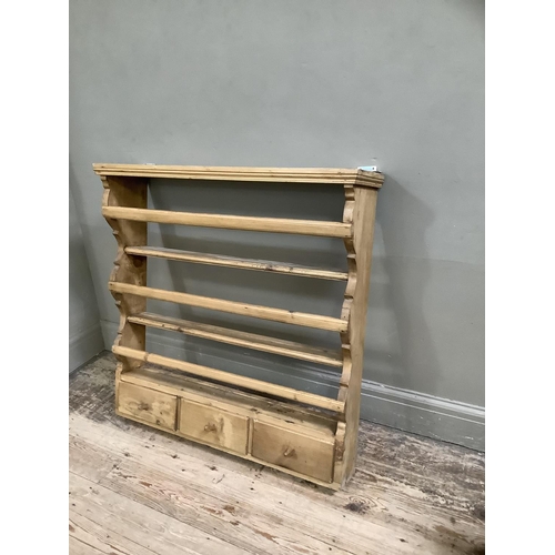 129 - A set of pine Delft hanging wall shelves with three plate racks above three short drawers with flare... 