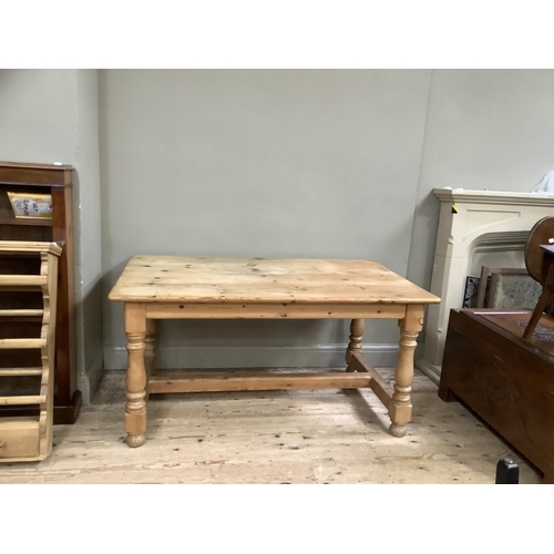 149 - A pine farmhouse dining table on turned legs with bun feet and cross stretcher, 150cm wide, 75cm hig... 