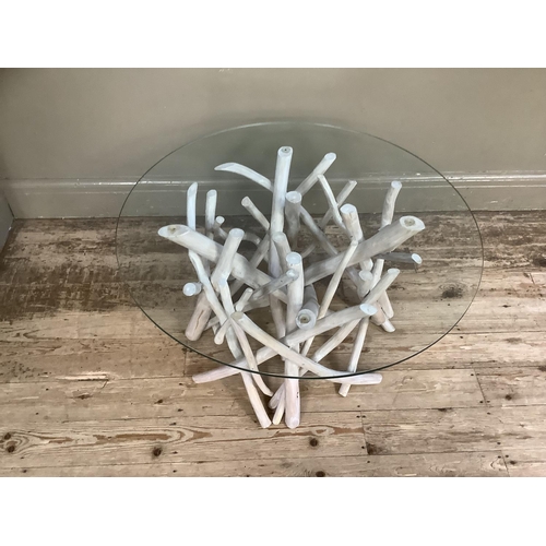 152 - A glass topped coffee table, the base entwined birch style branches, measuring 80cm diameter, 43cm h... 