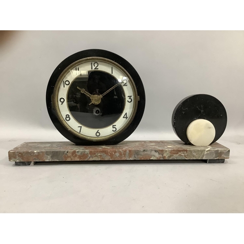 287 - An Art Deco mantel clock, the circular dial with black Arabic numerals on a rouge marble plinth base... 