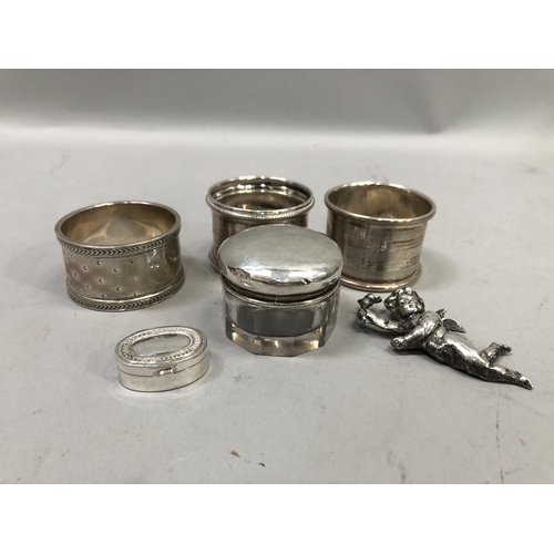 357 - Three early 20th century silver napkin rings together with a silver topped jar, a pill box and cheru... 