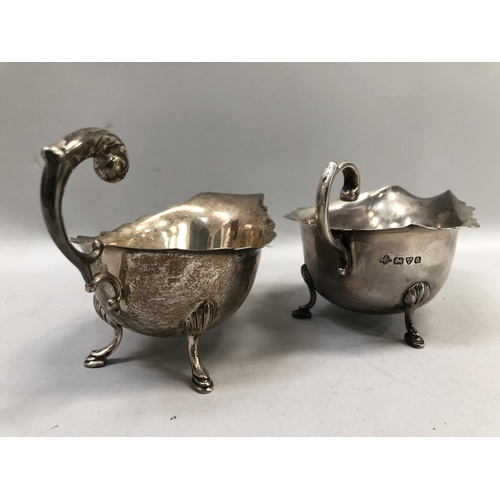 369 - A George V silver sauce boat, with incised rim, 'C' scroll handle and scalloped pad feet, hallmarked... 