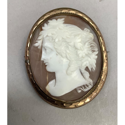 413 - A Victorian shell cameo brooch in gilt base metal, the oval female portrait with vine dressed hair c... 