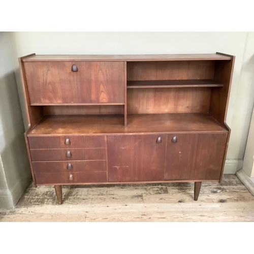 123 - A 1960/70s teak side cabinet with fall down front above four short drawers, two door cupboard openin... 