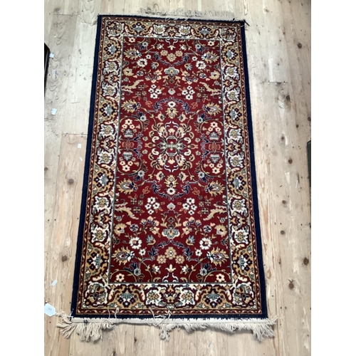 540 - A rectangular wool rug with claret red central panel, floral decoration surmounted by Royal blue bor... 