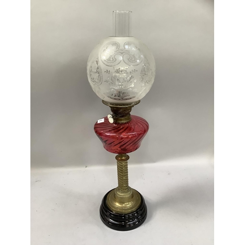 62 - A Victorian brass oil lamp, having a cranberry glass reservoir, writhen column and etched globular s... 