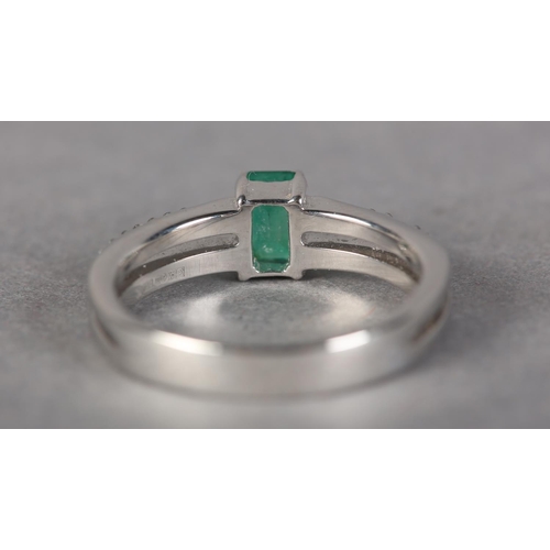 185 - AN EMERALD AND DIAMOND RING IN 18CT WHITE GOLD, claw set to the centre with a step cut emerald flank... 