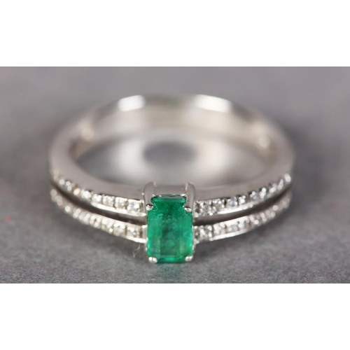 185 - AN EMERALD AND DIAMOND RING IN 18CT WHITE GOLD, claw set to the centre with a step cut emerald flank... 