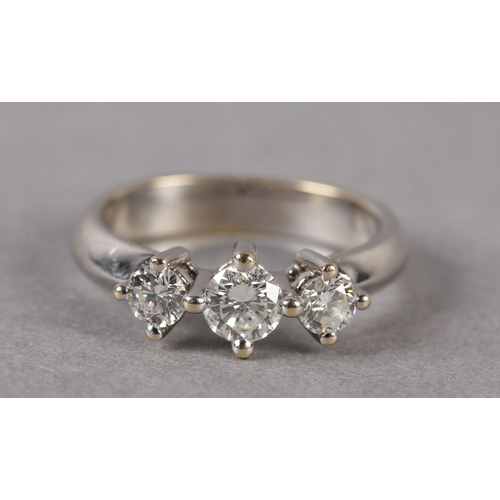 173 - A THREE STONE DIAMOND RING, the graduated brilliant cut stones each in a four claw setting in a spac... 