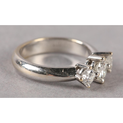 173 - A THREE STONE DIAMOND RING, the graduated brilliant cut stones each in a four claw setting in a spac... 