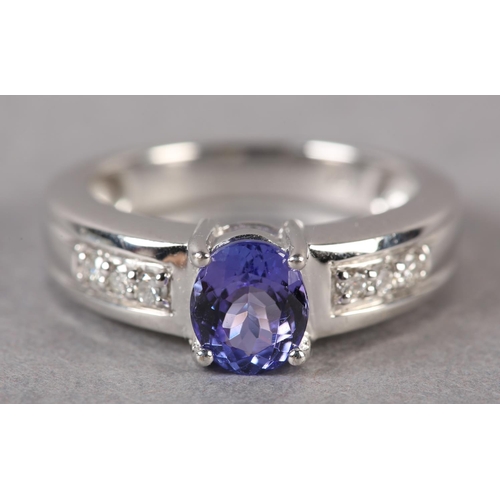 174 - A TANZANITE AND DIAMOND RING in 18ct white gold by Iliana, claw set to the centre with an oval facet... 