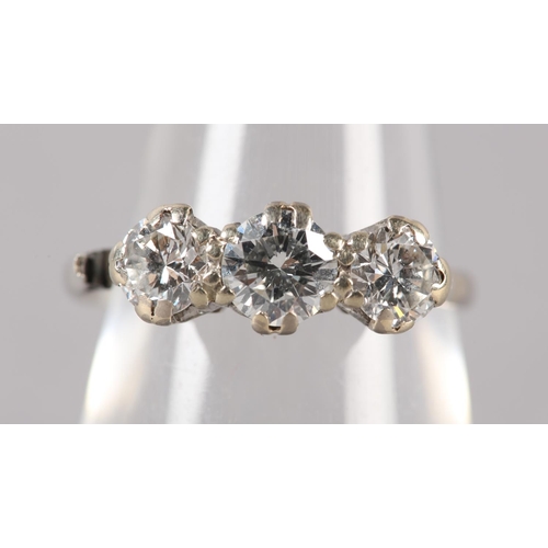 176 - A THREE STONE DIAMOND RING in platinum, c1960, the graduated brilliant cut stones claw set in line, ... 