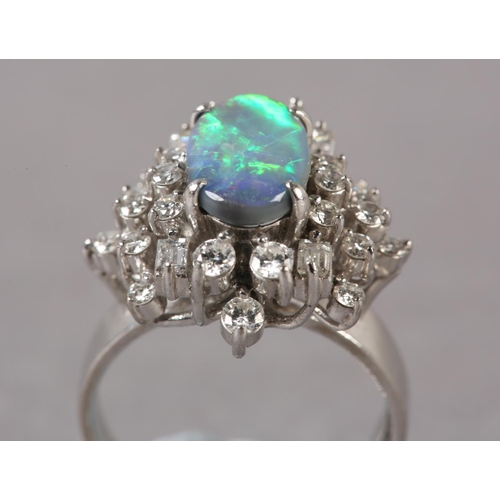 169 - A BLACK OPAL AND DIAMOND CLUSTER RING, the oval cabochon opal claw set and raised against a tiered s... 