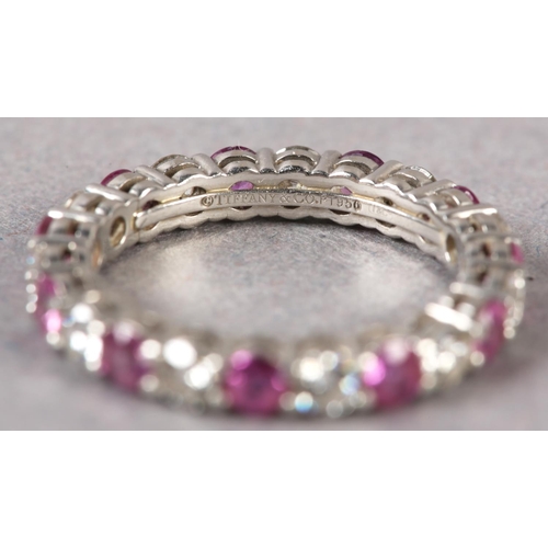 177 - A RUBY AND DIAMOND ETERNITY RING BY TIFFANY AND CO in platinum, the circular faceted rubies and bril... 