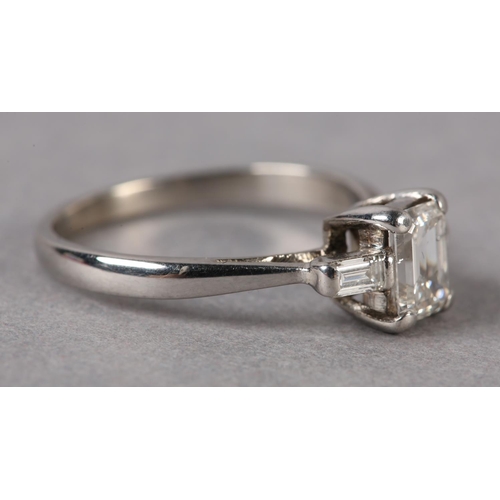 199 - A THREE STONE DIAMOND RING, claw set to the centre with a step cut stone flanked by two baguette cut... 