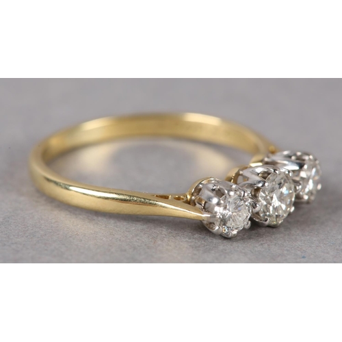 208 - A THREE STONE DIAMOND RING in 18ct yellow and white gold, the graduated brilliant cut stones claw se... 