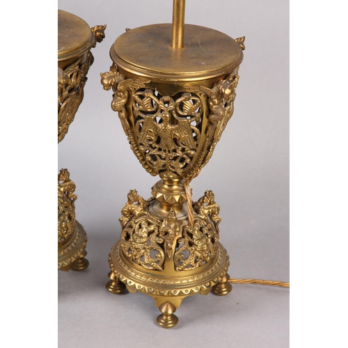 11 - A PAIR OF LATE VICTORIAN GILT METAL TABLE LAMPS, the pierced basket body having four panels cast wit... 