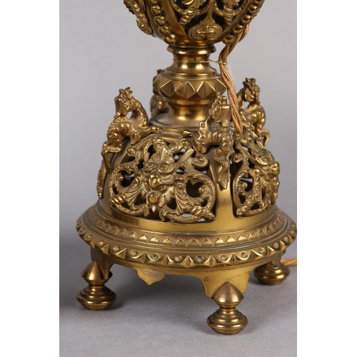 11 - A PAIR OF LATE VICTORIAN GILT METAL TABLE LAMPS, the pierced basket body having four panels cast wit... 