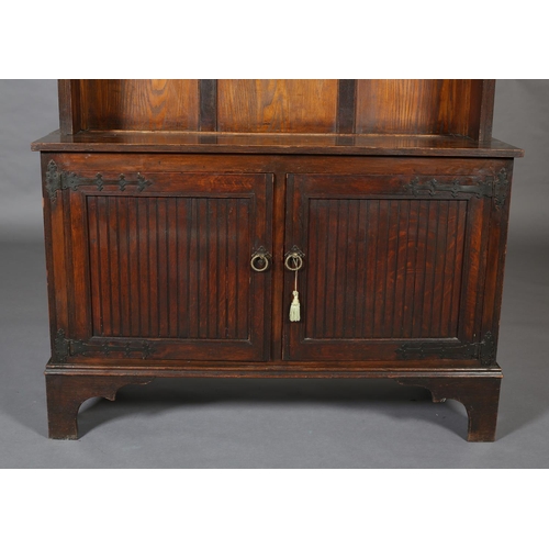 412 - AN ARTS & CRAFTS OAK BOOKCASE-CUPBOARD, having a triangular pediment above three shelves with hinged... 