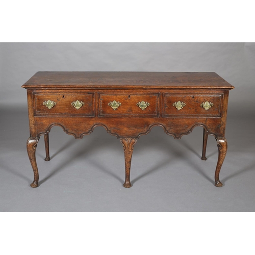 425 - AN 18th CENTURY-STYLE OAK DRESSER BASE, having three field-panelled drawers across with brass plates... 