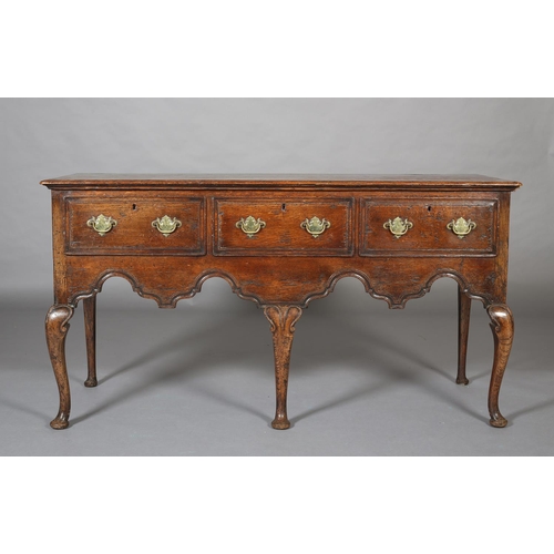 425 - AN 18th CENTURY-STYLE OAK DRESSER BASE, having three field-panelled drawers across with brass plates... 