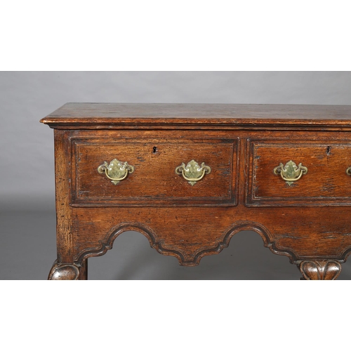 425 - AN 18th CENTURY-STYLE OAK DRESSER BASE, having three field-panelled drawers across with brass plates... 