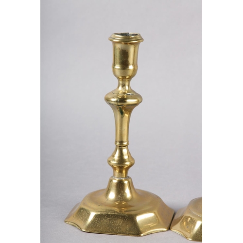 57 - A PAIR OF EARLY 18TH CENTURY BRASS CANDLESTICKS, having a cylindrical sconce, inverted baluster stem... 