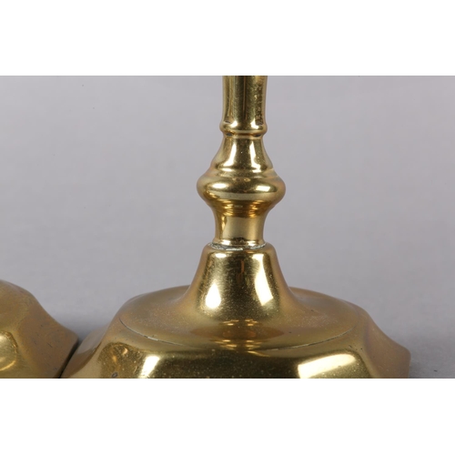 57 - A PAIR OF EARLY 18TH CENTURY BRASS CANDLESTICKS, having a cylindrical sconce, inverted baluster stem... 