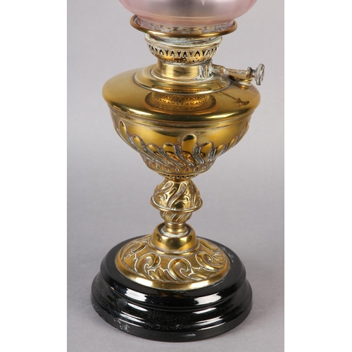 13 - A VICTORIAN BRASS OIL LAMP, with wrythen lobed reservoir and scrolled base on a black glass plinth, ... 