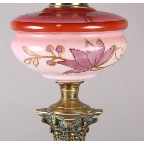 17 - A VICTORIAN BRASS CORINTHIAN COLUMN OIL LAMP, pink tinted and gilt floral reservoir, on stepped squa... 