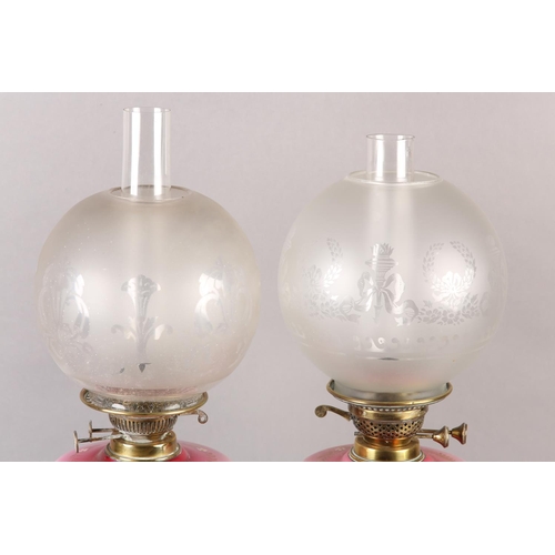 21 - A NEAR PAIR OF VICTORIAN BRASS OIL LAMPS, the pink tinted reservoirs painted with mauve flower heads... 