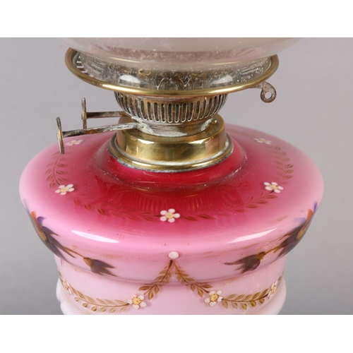 21 - A NEAR PAIR OF VICTORIAN BRASS OIL LAMPS, the pink tinted reservoirs painted with mauve flower heads... 