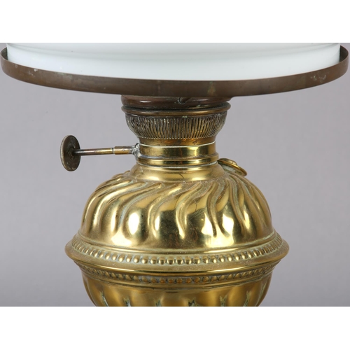 24 - A VICTORIAN BRASS OIL LAMP having a wrythen embossed 'cup and cover' reservoir and conforming domed ... 