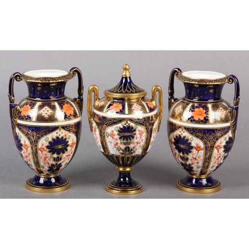 100 - A PAIR OF ROYAL CROWN DERBY IMARI PATTERN urn vases with date cyphers for 1925 together with a lidde... 