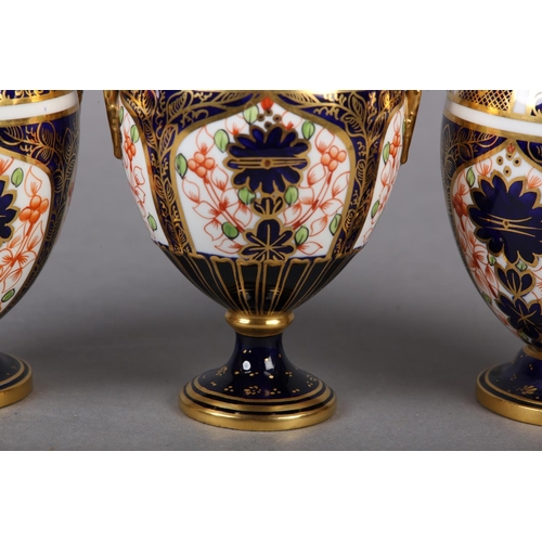 100 - A PAIR OF ROYAL CROWN DERBY IMARI PATTERN urn vases with date cyphers for 1925 together with a lidde... 