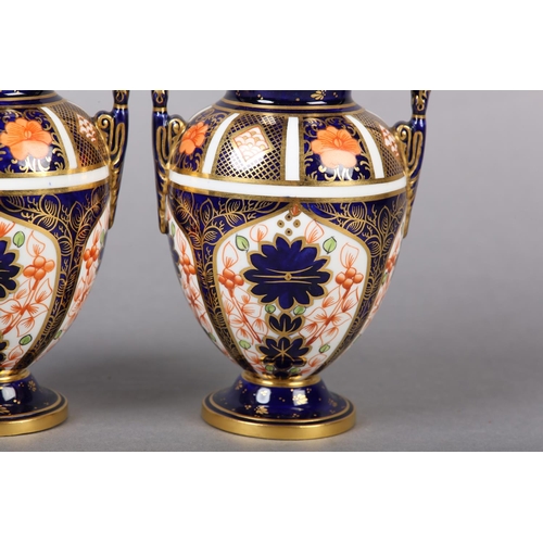 100 - A PAIR OF ROYAL CROWN DERBY IMARI PATTERN urn vases with date cyphers for 1925 together with a lidde... 