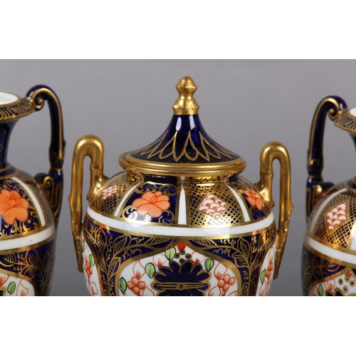 100 - A PAIR OF ROYAL CROWN DERBY IMARI PATTERN urn vases with date cyphers for 1925 together with a lidde... 