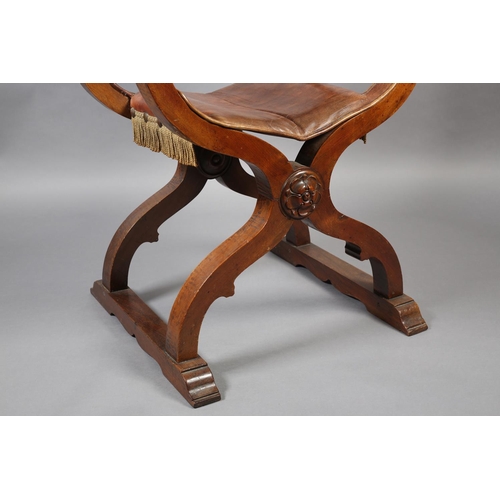 383 - A LATE 19TH CENTURY FRUITWOOD FOLDING 'X' FRAME CHAIR, having a hide sling back, leaf carved arms wi... 