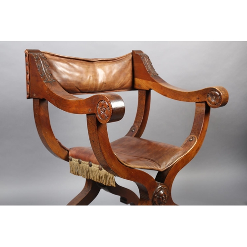 383 - A LATE 19TH CENTURY FRUITWOOD FOLDING 'X' FRAME CHAIR, having a hide sling back, leaf carved arms wi... 