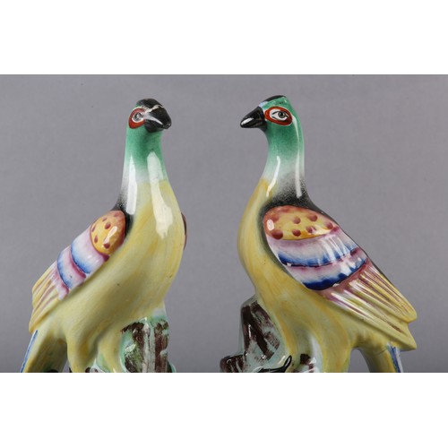 94 - A PAIR OF MID-19TH CENTURY STAFFORDSHIRE BIRDS WITH MULTICOLOURED PLUMAGE, perched on a rocky outcro... 