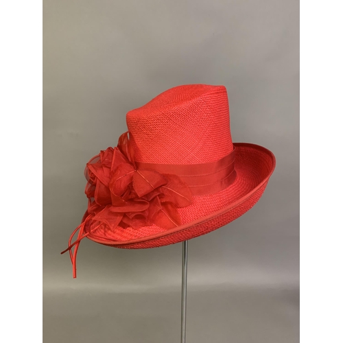 247 - Cosmo Jenks asymmetrical red straw hat with organza rose detail to the grosgrain ribbon, contained i... 