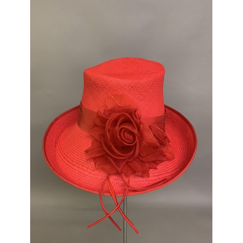 247 - Cosmo Jenks asymmetrical red straw hat with organza rose detail to the grosgrain ribbon, contained i... 