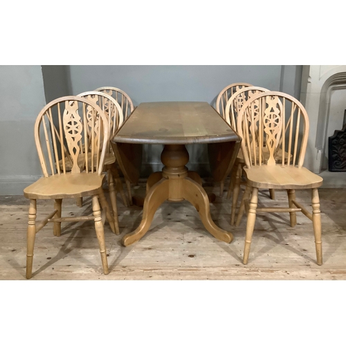 119 - A pine drop leaf circular dining table with baluster support and six kitchen dining chairs