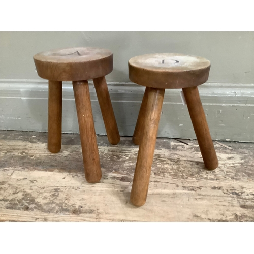 128 - A pair of two oak milking stools on three legs, the circular tops carved with A and D, 24.5cm wide