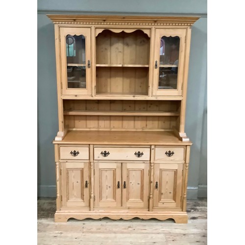 233 - A pine sideboard having two glazed doors above a base of three drawers above three doors