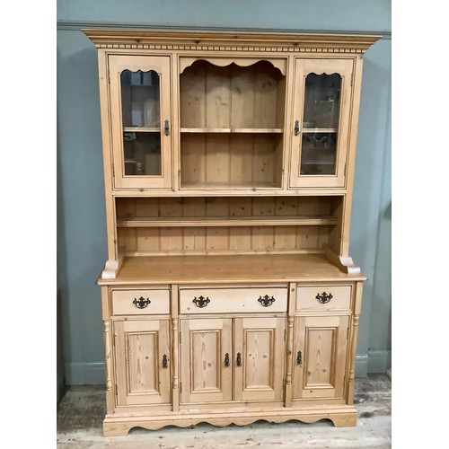 233 - A pine sideboard having two glazed doors above a base of three drawers above three doors